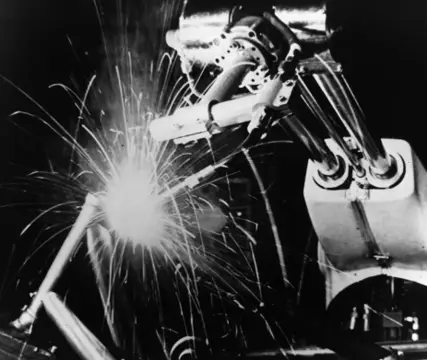Historical photograph of early welding automation machinery from the 1960s